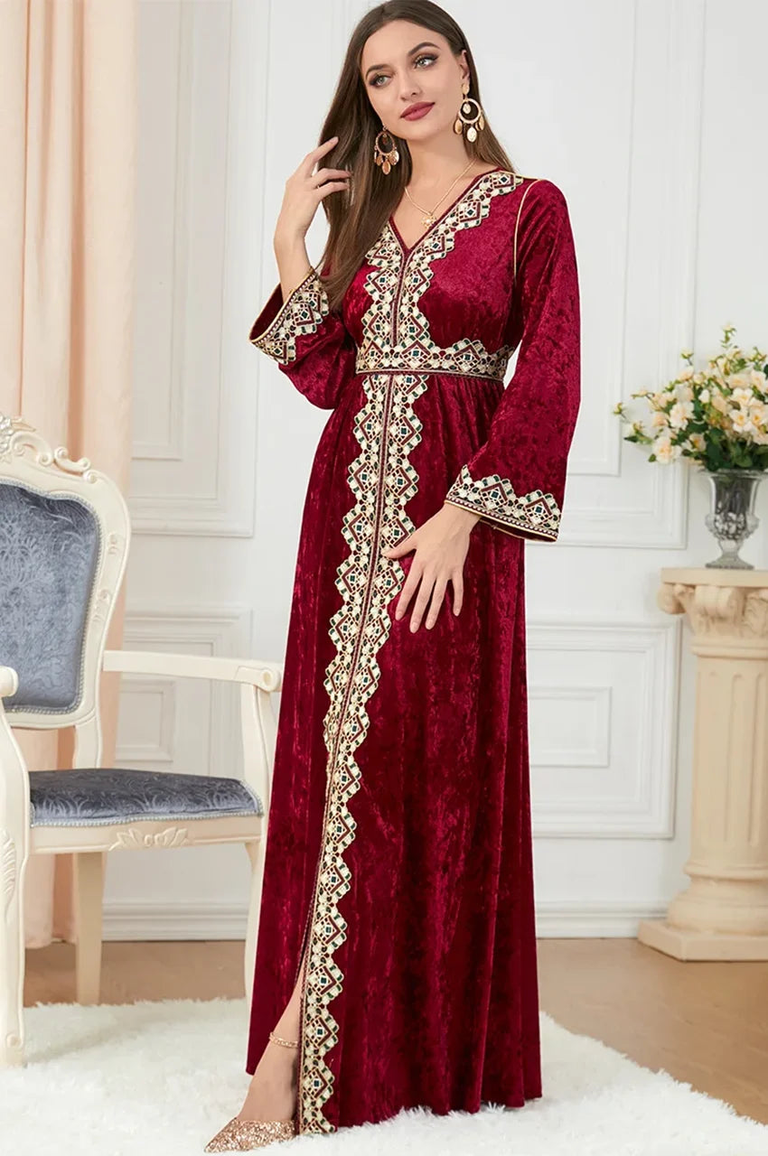 Elegant pose of model wearing Zaynah red Moroccan velvet kaftan in luxury interior